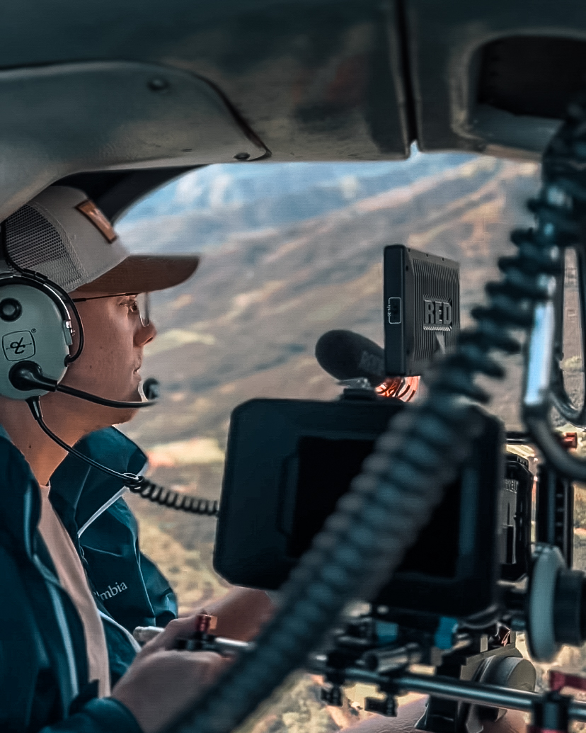 Jan Hendrik Eming sits with a RED V-Raptor 8K Cinema Camera in a Helicopter while flying over the Island of Maui, Hawaii to film the Swimmer André Wiersig.